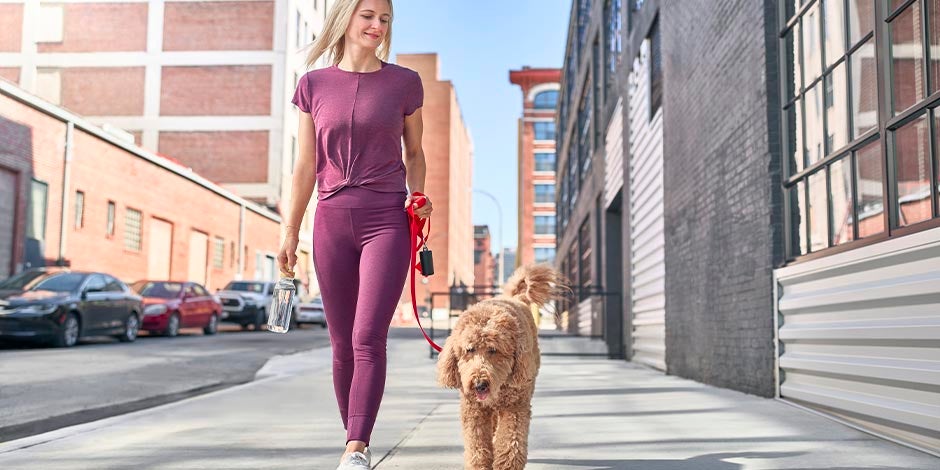 Beneficios de tener un perro – Paseo Hay beneficios en el cuerpo de un tutor al tener un perro. Mujer paseando a su mascota.