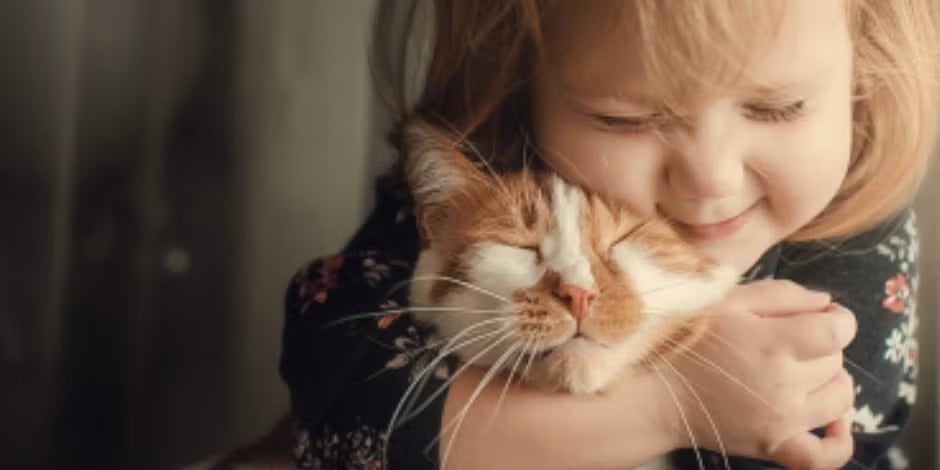 Los nombres para gatos adecuados para tu michi deben ser elegidos cuidadosamente. Niña abrazando a su minino.