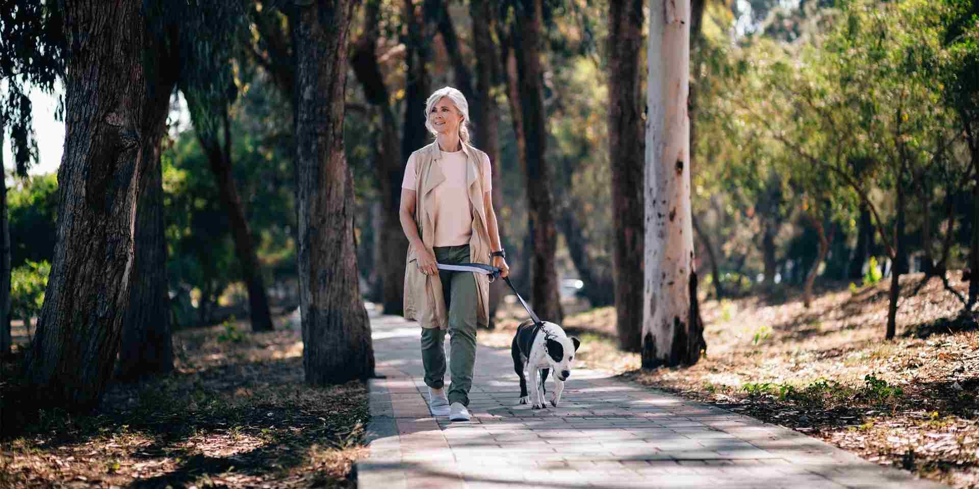 Un paseo tranquilo puede aliviar el hipo en perros. Tutora con su mascota.