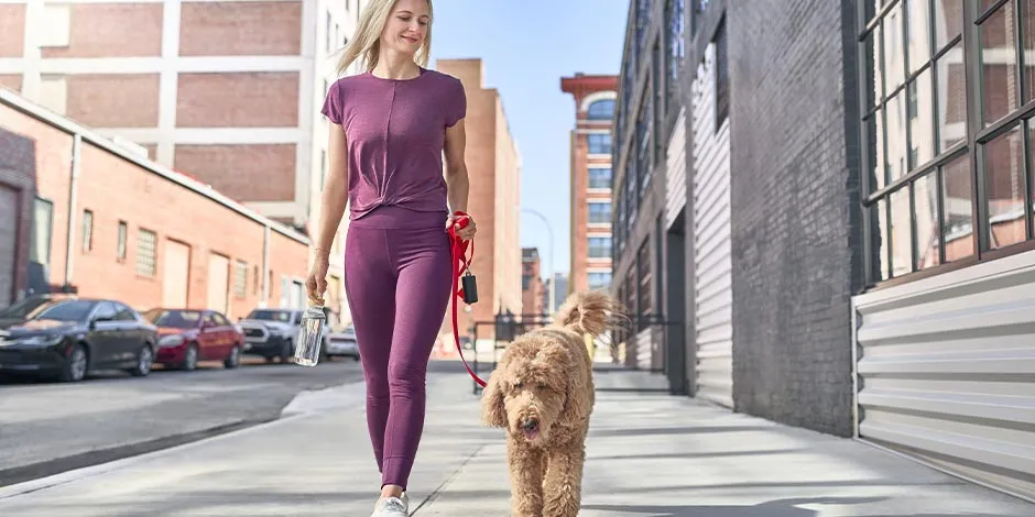 Hay beneficios en el cuerpo de un tutor al tener un perro. Mujer paseando a su mascota.